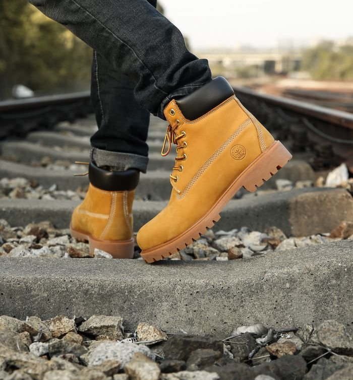 Services Close-up of yellow boots walking on railway tracks, showcasing adventure and style.