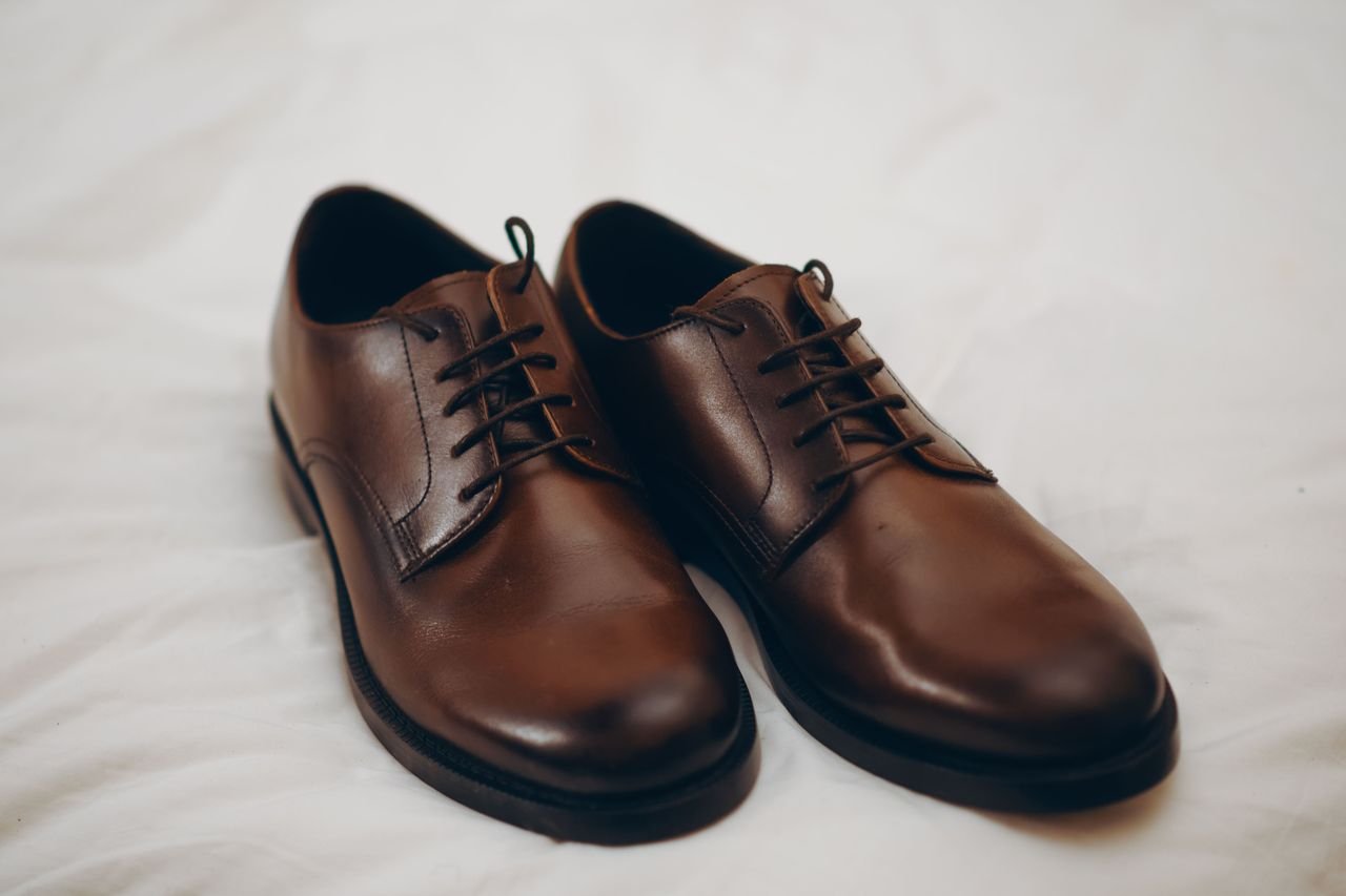 Home Pair of classic brown leather dress shoes resting on a white surface.