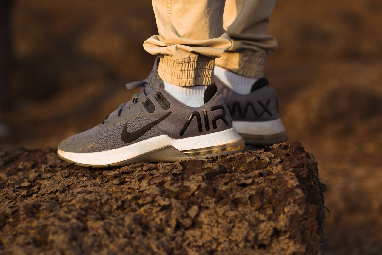 Services Close-up of athletic sneakers worn atop a rocky surface outdoors at sunset.
