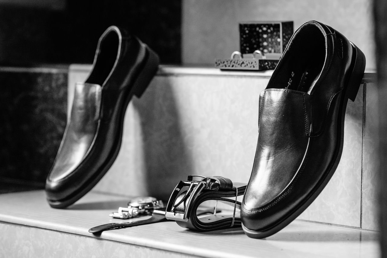 Mastering the First Impression: Your intriguing post title goes here Stylish black leather formal shoes paired with accessories in a black and white setting.