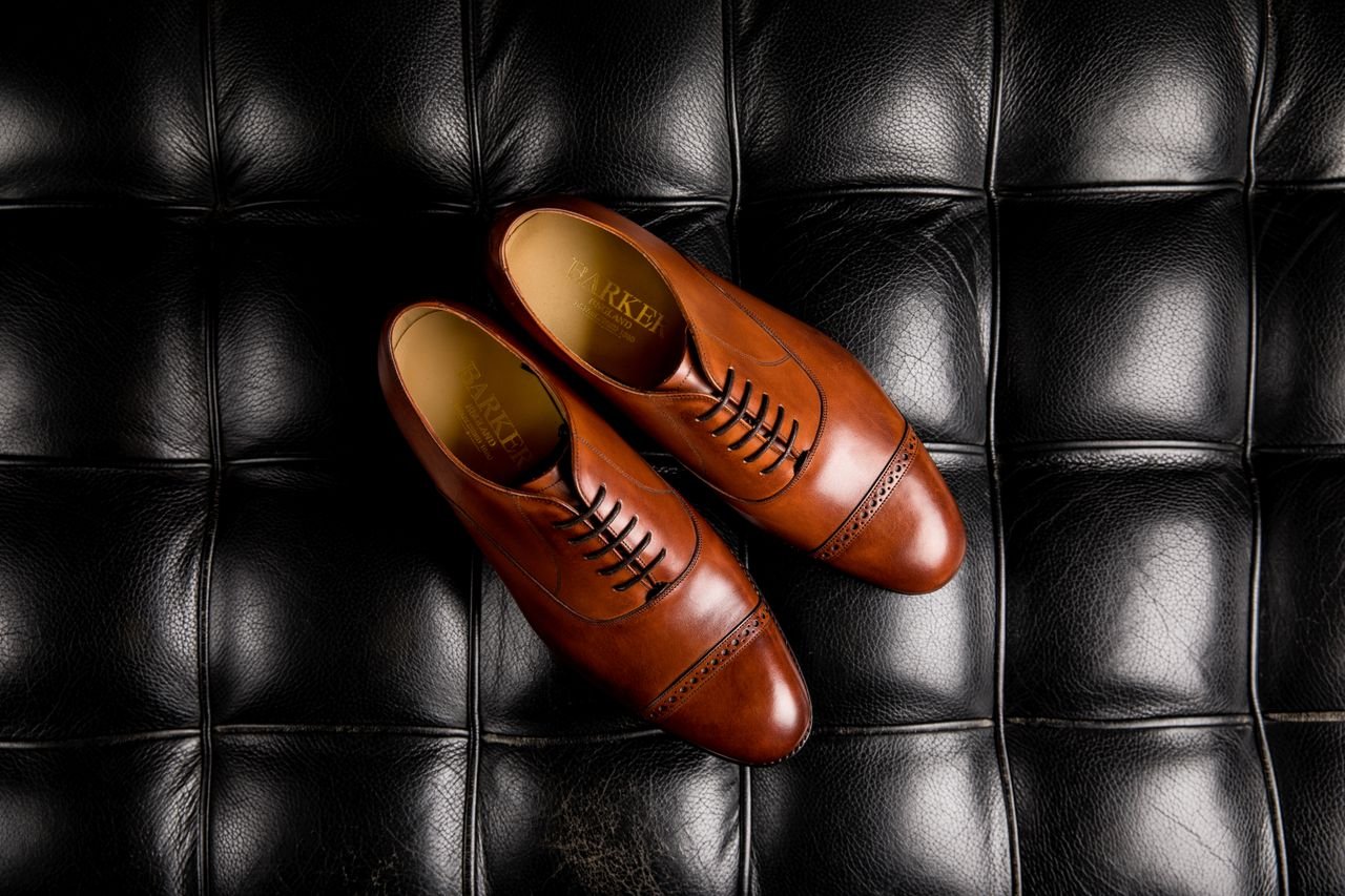 About Pair of elegant brown leather oxford shoes displayed on a quilted black leather surface.